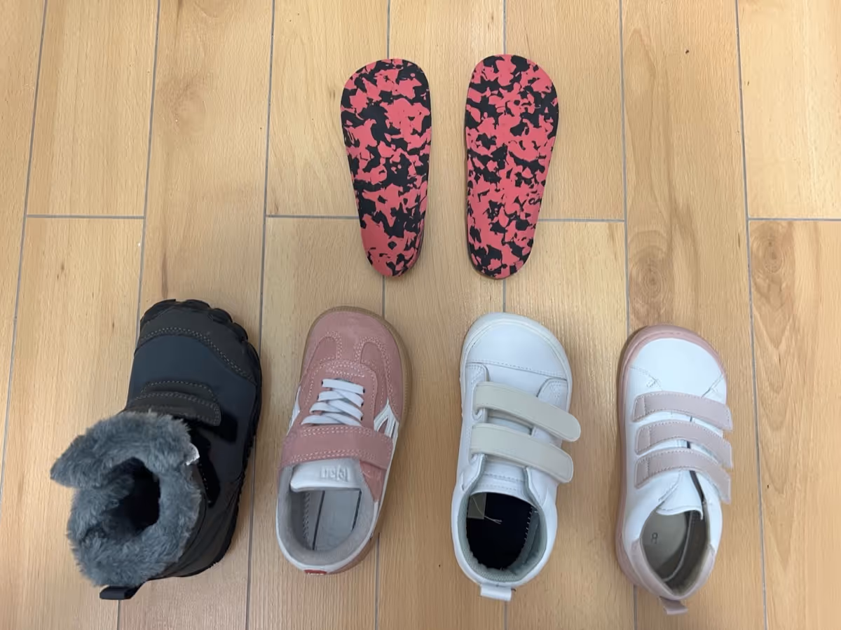 Soportes plantares personalizados junto a cuatro pares de zapatos infantiles revisados en Centro Podológico Henao para tratamiento ortopodológico